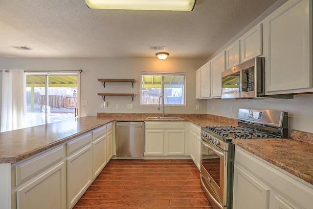 kitchen with white cabinetry, sink, kitchen peninsula, and appliances with stainless steel finishes