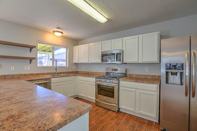 kitchen featuring hardwood / wood-style floors, white cabinetry, sink, stainless steel appliances, and a textured ceiling