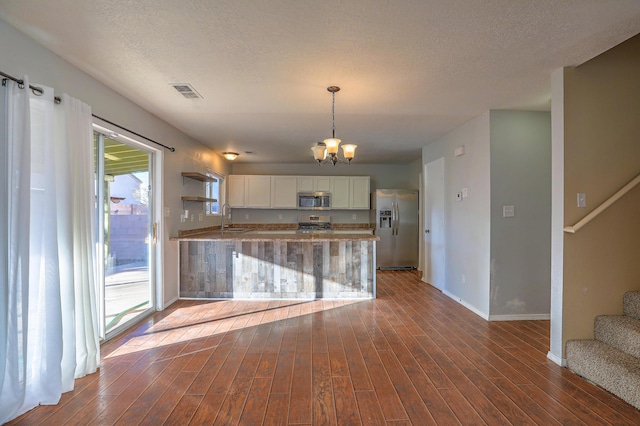 kitchen with dark wood-type flooring, sink, appliances with stainless steel finishes, kitchen peninsula, and white cabinets