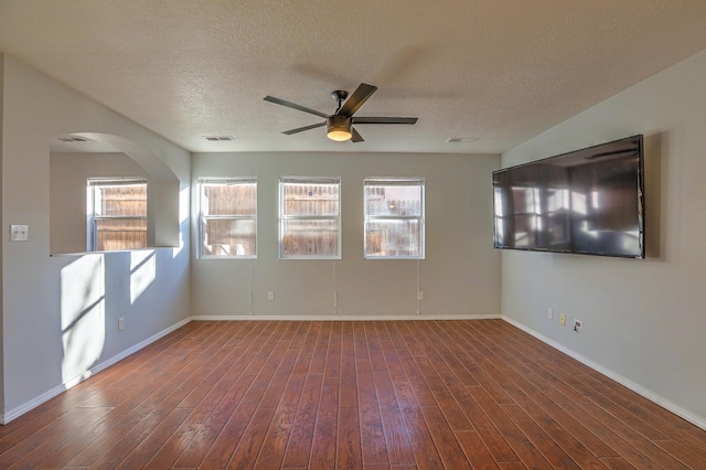 empty room with ceiling fan, dark hardwood / wood-style flooring, and a textured ceiling