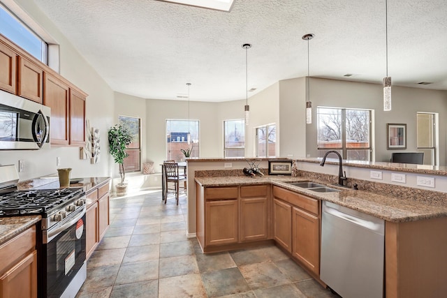 kitchen featuring stainless steel appliances, sink, a wealth of natural light, and decorative light fixtures