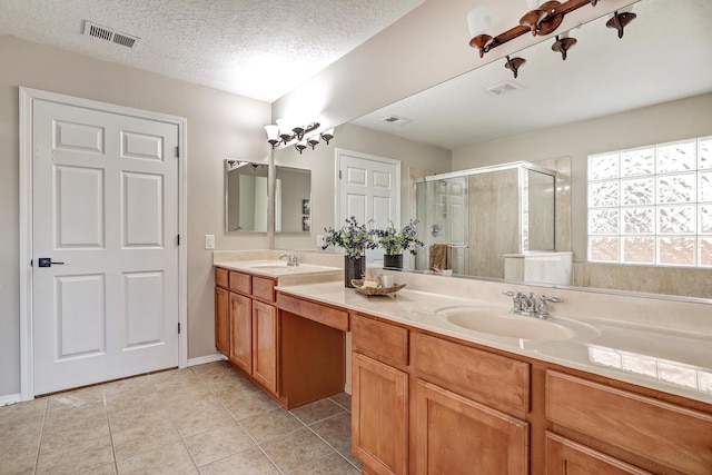 bathroom with tile patterned floors, vanity, an enclosed shower, and a textured ceiling