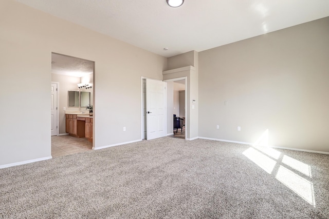 unfurnished bedroom with light carpet, connected bathroom, and a textured ceiling