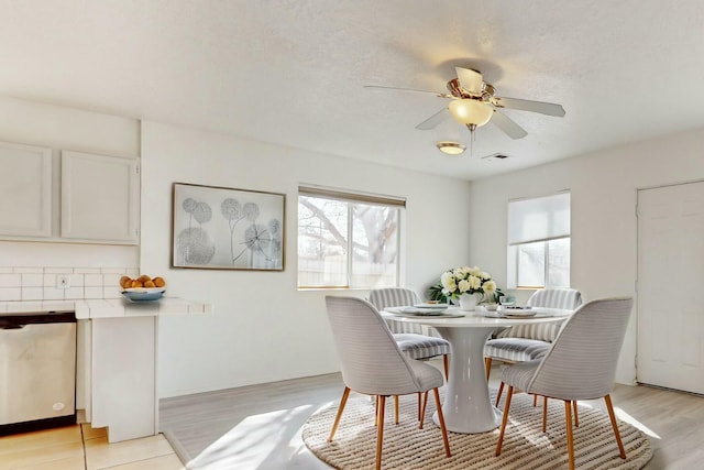 dining room featuring ceiling fan, a wealth of natural light, light hardwood / wood-style floors, and a textured ceiling