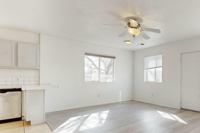 unfurnished living room featuring ceiling fan, a textured ceiling, and light wood-type flooring