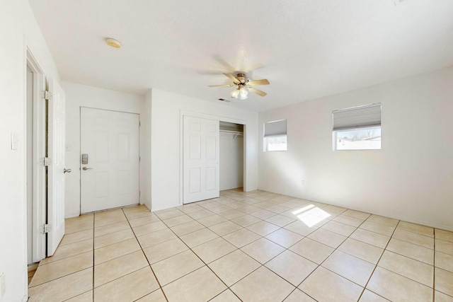 unfurnished bedroom with light tile patterned flooring, ceiling fan, and a closet