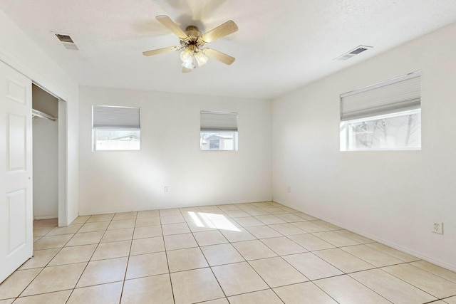 spare room featuring ceiling fan, light tile patterned floors, and a wealth of natural light