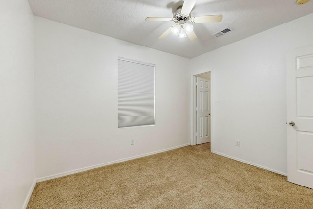 empty room featuring ceiling fan, light colored carpet, and a textured ceiling