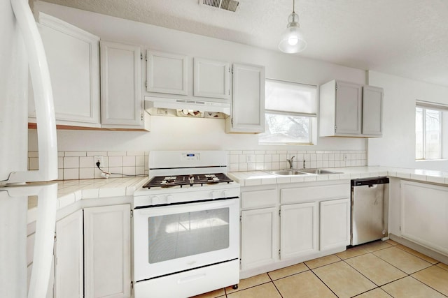 kitchen featuring tile counters, dishwasher, white range with gas stovetop, and decorative light fixtures