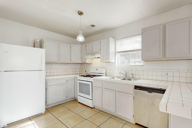 kitchen with sink, white appliances, white cabinetry, tile counters, and decorative light fixtures