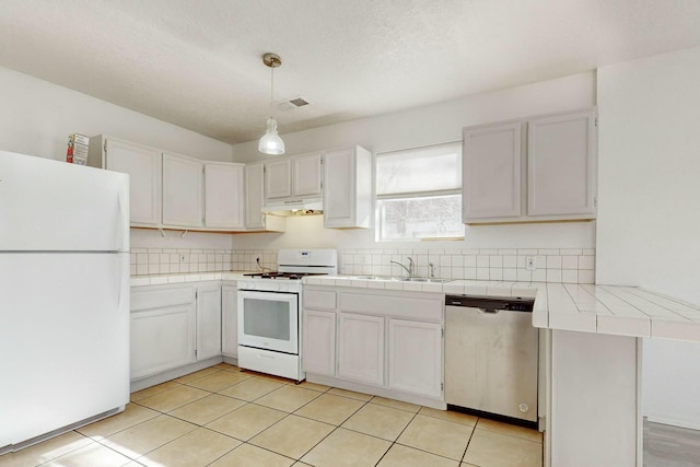 kitchen featuring decorative light fixtures, white cabinets, tile counters, kitchen peninsula, and white appliances