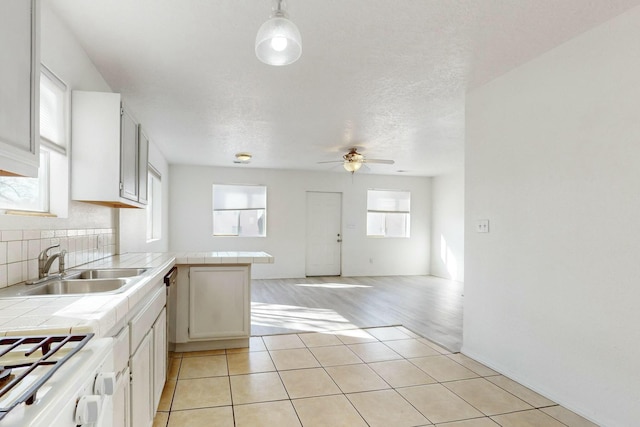 kitchen featuring sink, white cabinets, decorative light fixtures, tile countertops, and kitchen peninsula