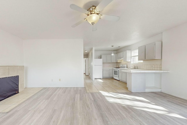 unfurnished living room with sink, ceiling fan, and light wood-type flooring