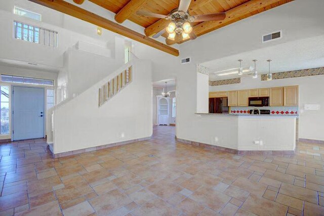 unfurnished living room with ceiling fan with notable chandelier, wooden ceiling, a towering ceiling, and beam ceiling