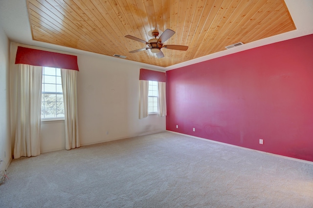 carpeted empty room with a raised ceiling, ceiling fan, plenty of natural light, and wood ceiling