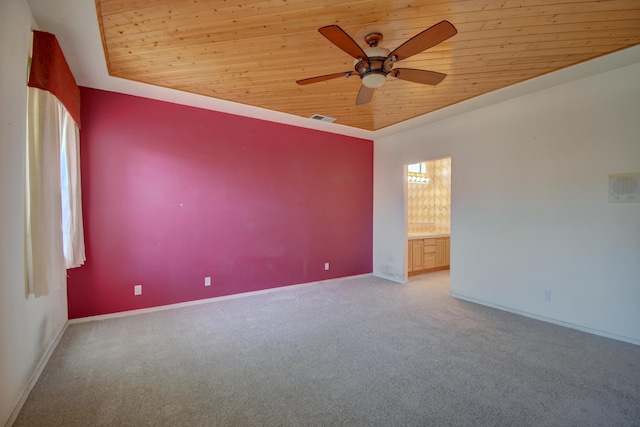 carpeted empty room featuring wood ceiling, ceiling fan, and a raised ceiling