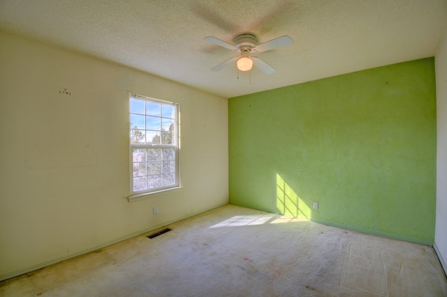 unfurnished room featuring ceiling fan, light colored carpet, and a textured ceiling