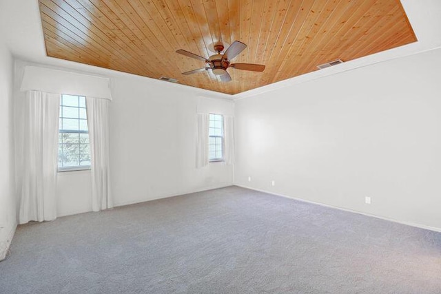 carpeted empty room featuring ceiling fan, crown molding, a wealth of natural light, and wooden ceiling