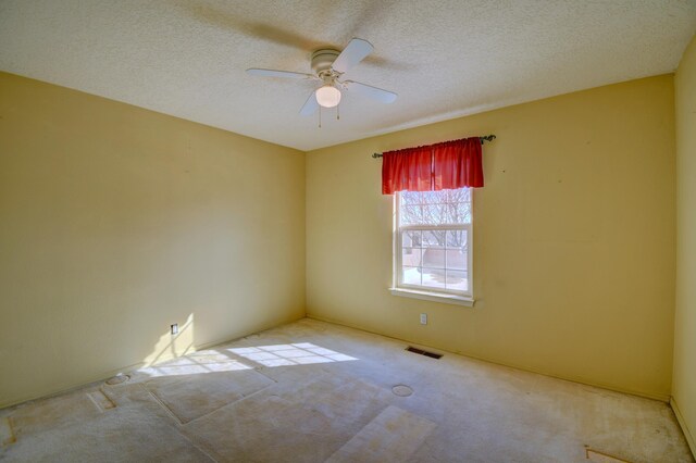 spare room with ceiling fan, light carpet, and a textured ceiling