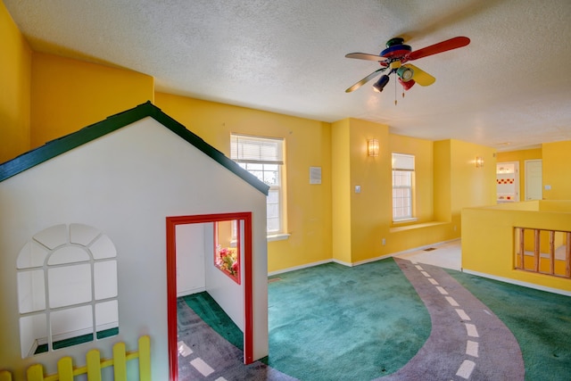 game room featuring ceiling fan, a textured ceiling, and carpet