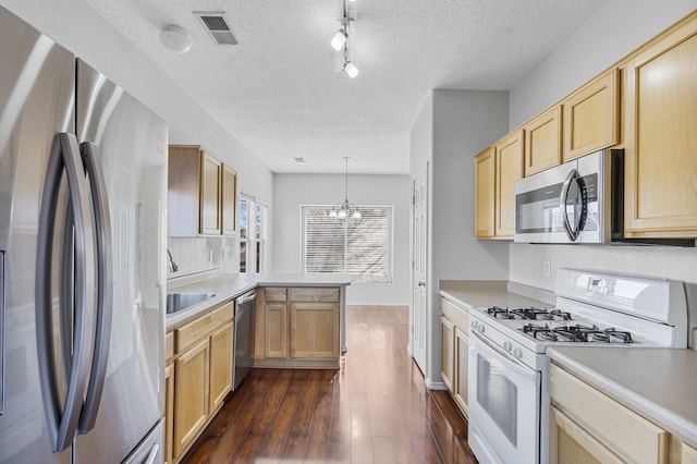 kitchen featuring light brown cabinetry, dark hardwood / wood-style flooring, kitchen peninsula, pendant lighting, and stainless steel appliances