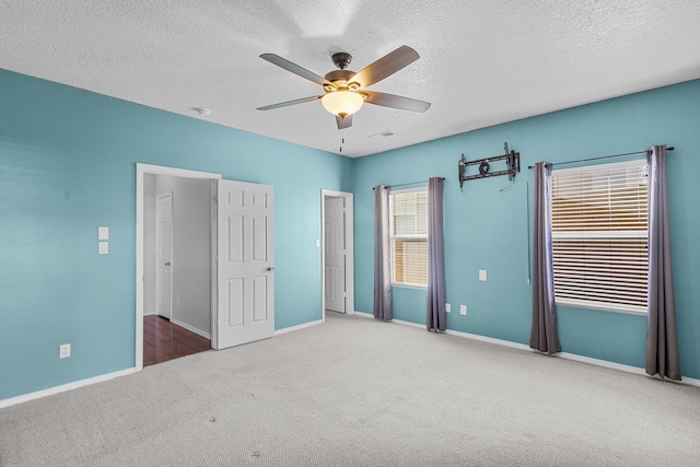 unfurnished bedroom with a textured ceiling, ceiling fan, and carpet