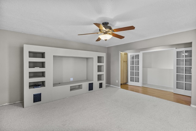 unfurnished living room with french doors, ceiling fan, carpet flooring, and a textured ceiling