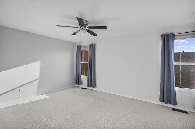 unfurnished room with ceiling fan, carpet flooring, and a textured ceiling