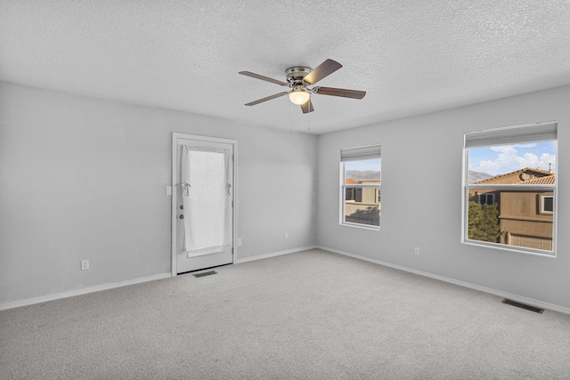 carpeted spare room with a textured ceiling and ceiling fan