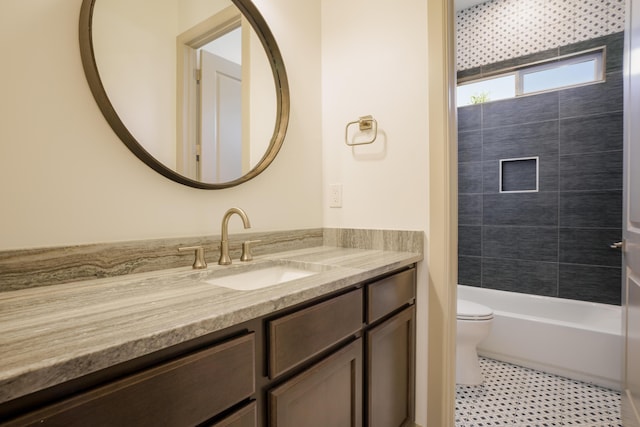 full bathroom featuring tiled shower / bath, vanity, and toilet