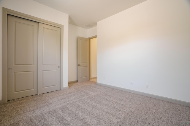 unfurnished bedroom featuring light carpet and a closet