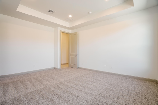 unfurnished room featuring a tray ceiling and carpet