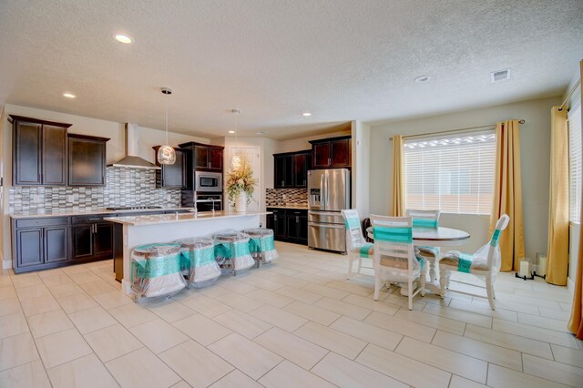 kitchen with pendant lighting, sink, ceiling fan, light stone countertops, and a textured ceiling