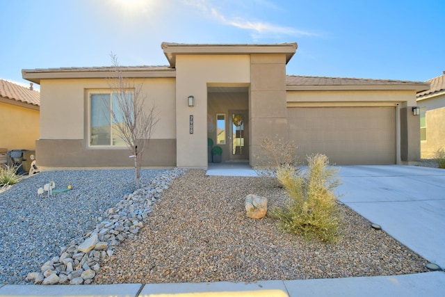 view of front of property with concrete driveway, an attached garage, a tiled roof, and stucco siding