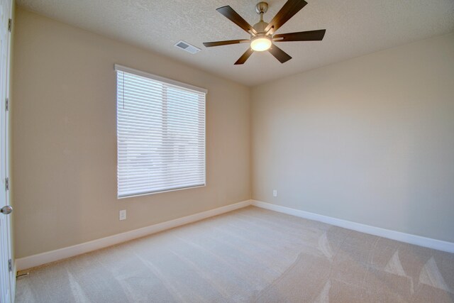 carpeted spare room featuring ceiling fan and a textured ceiling