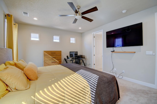 bedroom featuring ceiling fan, light colored carpet, and a textured ceiling