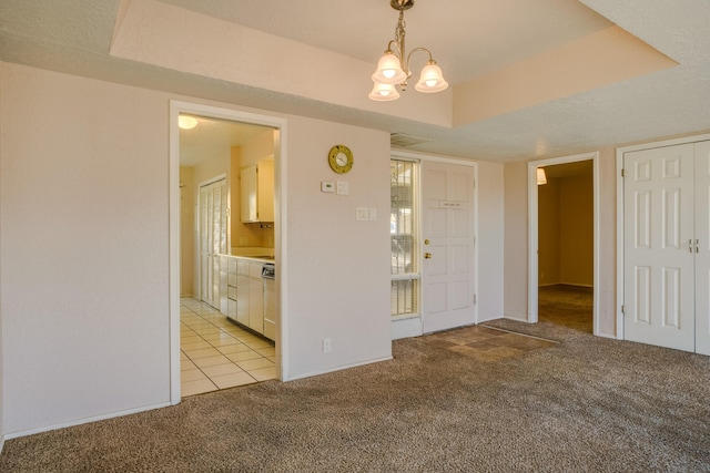 empty room featuring a raised ceiling, light carpet, and an inviting chandelier