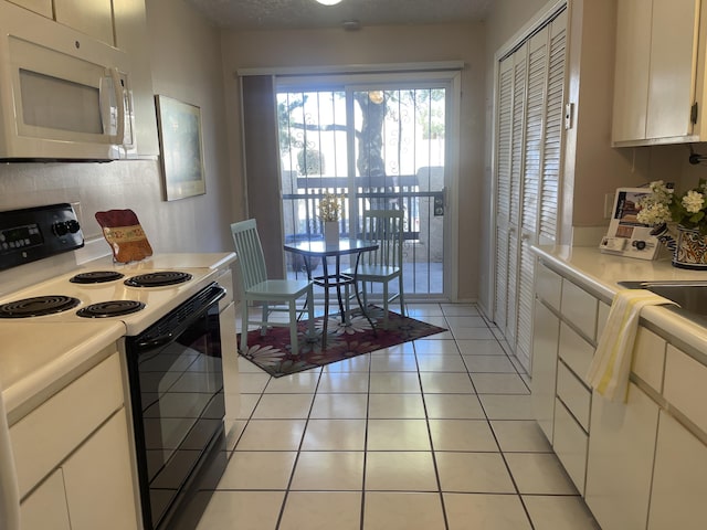 kitchen featuring light tile patterned floors, range with electric stovetop, and white cabinets