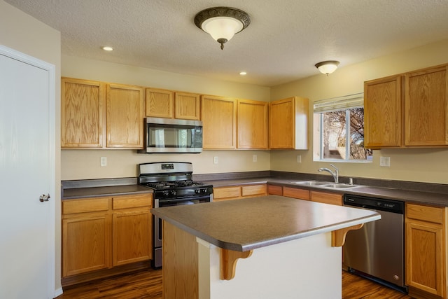 kitchen featuring sink, a breakfast bar, stainless steel appliances, a center island, and a textured ceiling