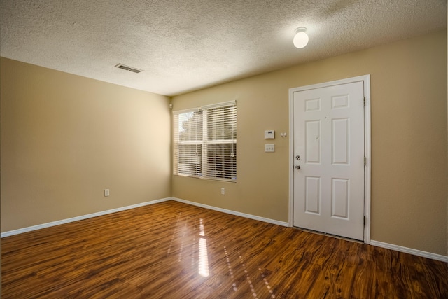 spare room featuring a textured ceiling and dark hardwood / wood-style flooring