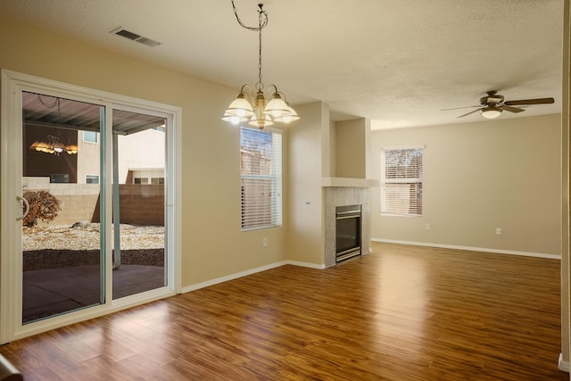 unfurnished living room featuring ceiling fan with notable chandelier, a fireplace, hardwood / wood-style floors, and a textured ceiling