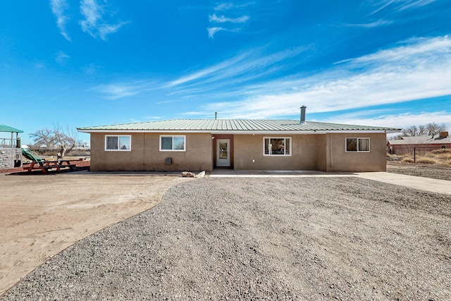 view of front of home with a playground, metal roof, fence, and stucco siding