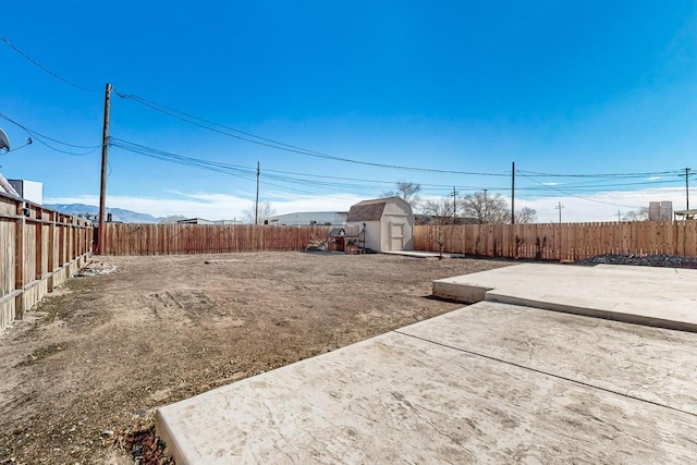 view of yard with a patio area, a shed, a fenced backyard, and an outbuilding