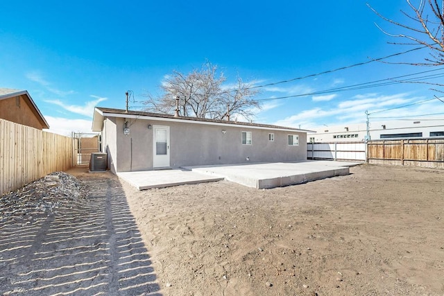 rear view of property with central air condition unit, stucco siding, a fenced backyard, and a patio