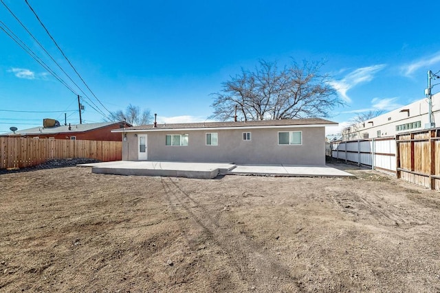 back of house with a fenced backyard, a patio, and stucco siding