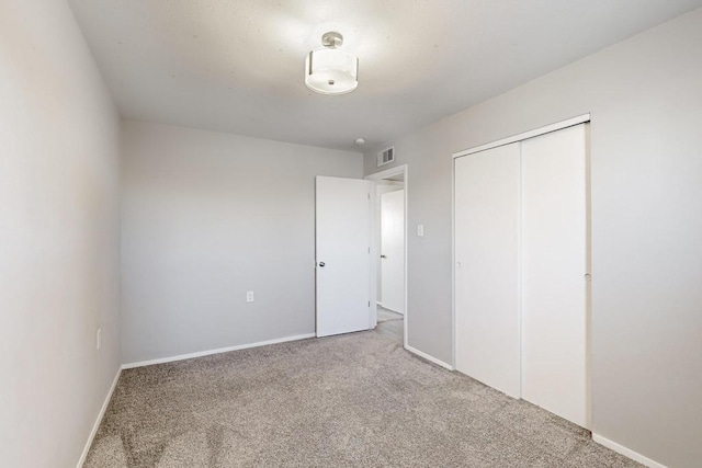 unfurnished bedroom featuring carpet, a closet, visible vents, and baseboards