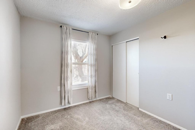 unfurnished bedroom with a textured ceiling, multiple windows, a closet, and light colored carpet