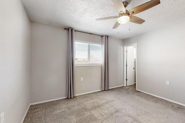 carpeted spare room with ceiling fan, baseboards, and a textured ceiling