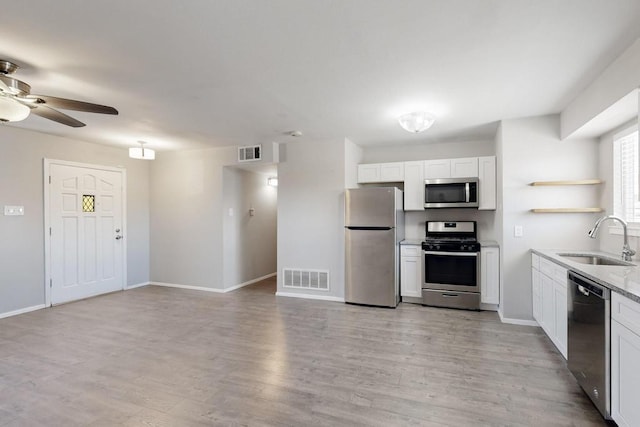 kitchen featuring open shelves, appliances with stainless steel finishes, a sink, and visible vents