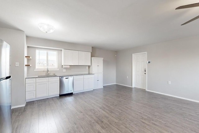 kitchen featuring baseboards, a ceiling fan, light wood-style flooring, stainless steel dishwasher, and a sink